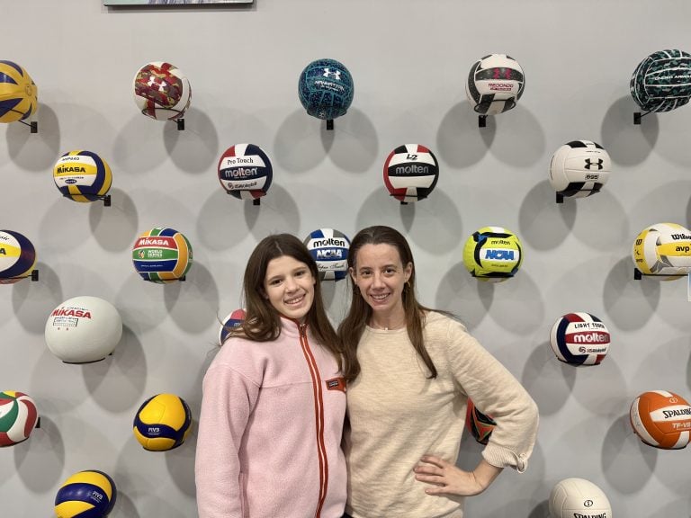 posing in front of a display of volleyballs at the International Volleyball Hall of Fame in Holyoke, MA