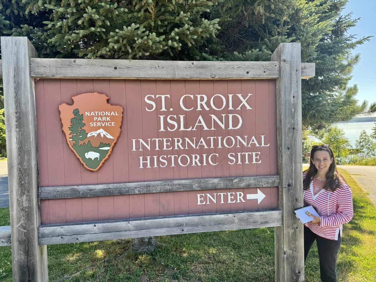 posing in front of the entrance sign to the view of the Saint Croix International Historic Park in Canada and Maine, USA
