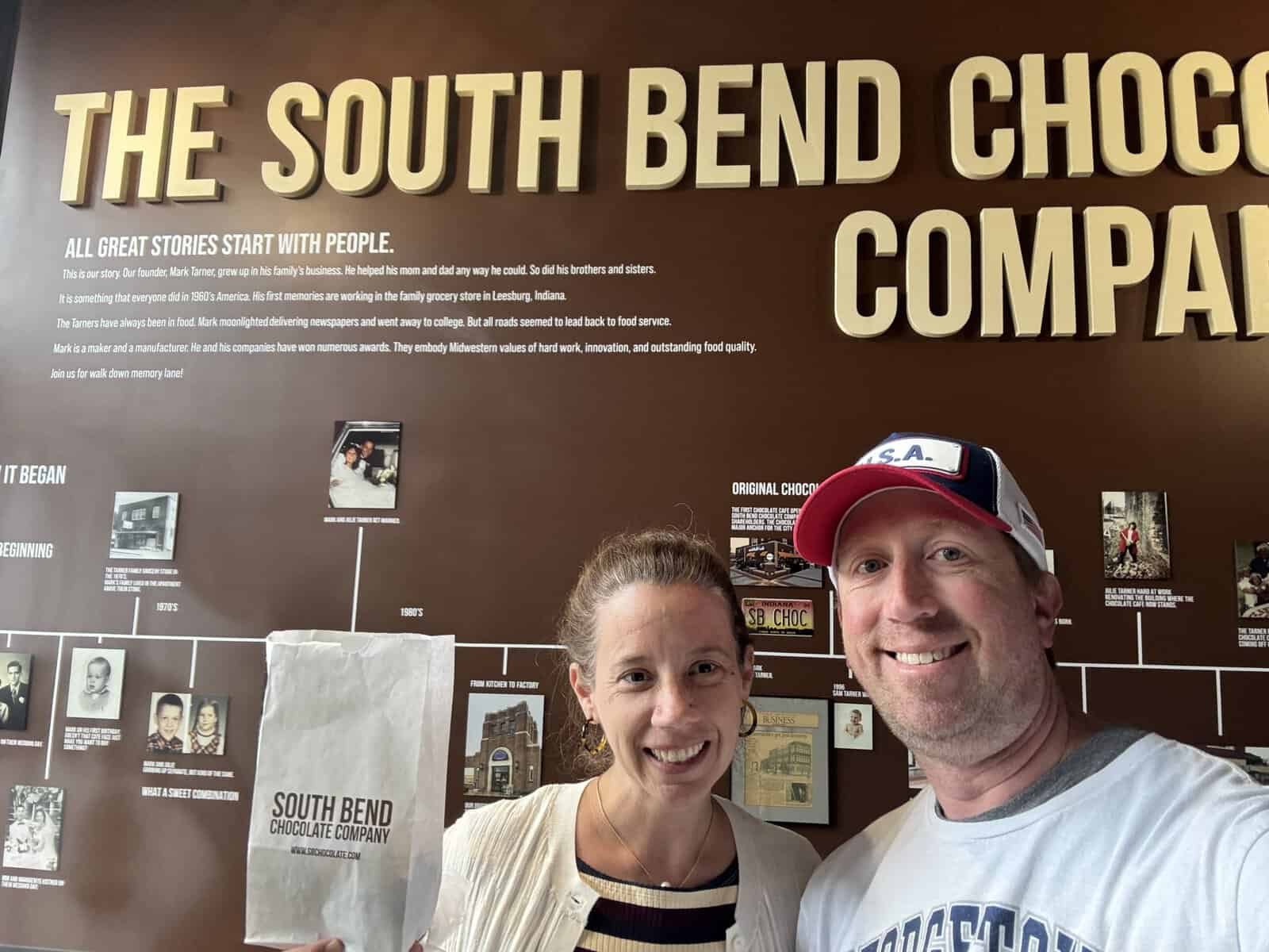 posing in front of the timeline at the South Bend Chocolate Factory in South Bend, IN